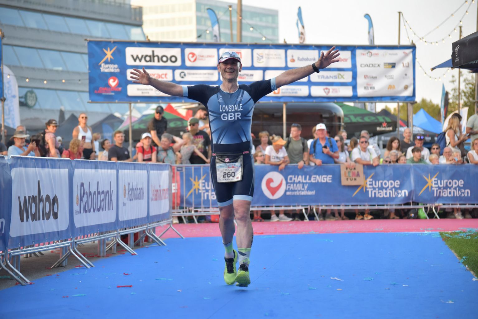 A man celebrating completing a triathlon after one to one coaching by Alpha State